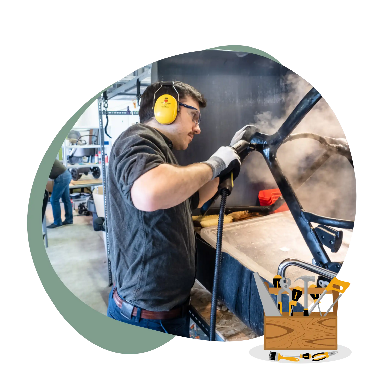 Ein Mann, der Gehörschutz und Schutzbrille trägt, benutzt einen Dampfreiniger an einem dunklen, möglicherweise metallischen Objekt, mit einem Werkzeugkasten-Grafik im Vordergrund.